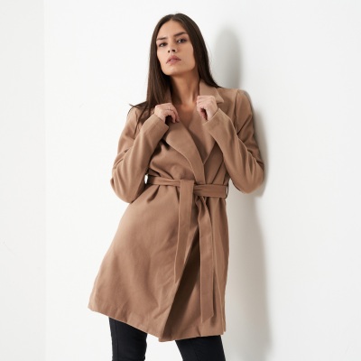 Apparel shot of a beige trench coat in studio light. By Nick van der Touw.
