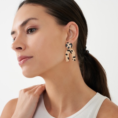 Profile shot of a woman wearing a leopard-print statement earring. By Nick van der Touw.