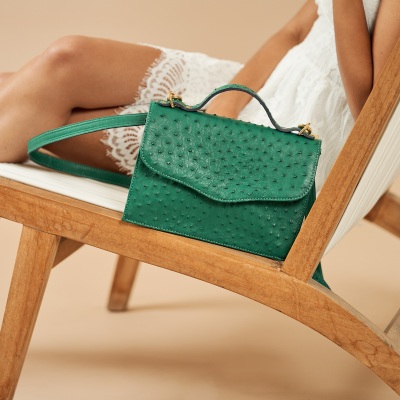 Product shot of a green ostrich-leather handbag on a chair. By Nick van der Touw.