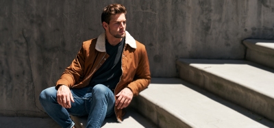 Menswear lifestyle shot of a man in a tan corduroy jacket on steps. By Nick van der Touw.