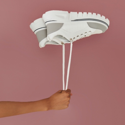 Product shot of a white cap against a mauve backdrop. By Nick van der Touw.
