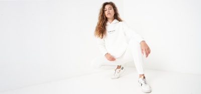 Athleisure shot of a woman in a white hoodie and joggers, crouching. By Nick van der Touw.