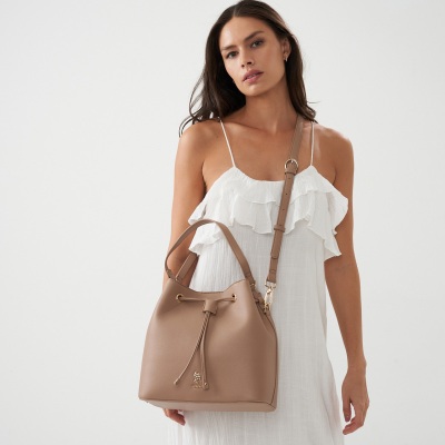 E-commerce shot of a white ruffle top with a tan bucket bag. By Nick van der Touw.