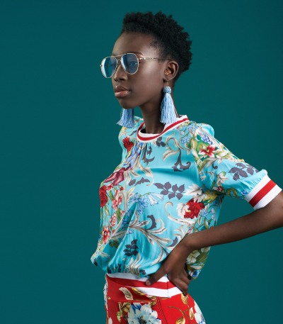 Fashion shot of a woman in a floral top against a teal backdrop. By Nick van der Touw.