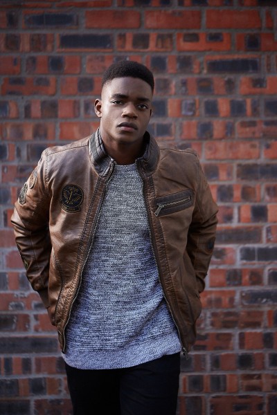 Fashion portrait of a man in a leather jacket against a brick wall. By Nick van der Touw.