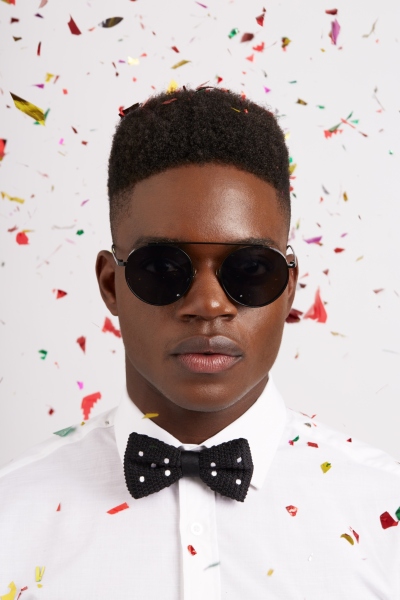 Studio portrait of a man in aviator sunglasses amid falling confetti. By Nick van der Touw.