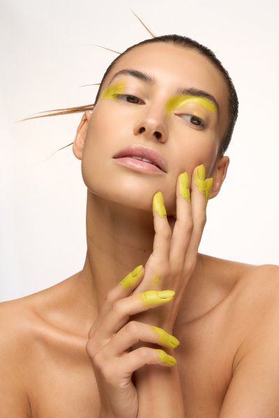 Serene beauty portrait of Albina with yellow nails cradling the face. Studio editorial by Nick van der Touw.