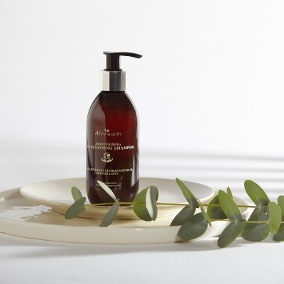 Product shot of a haircare shampoo bottle on a plate with leaves. By Nick van der Touw.