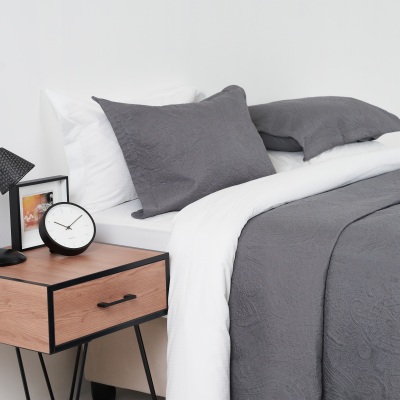 Homeware shot of grey bedding and cushions with an alarm clock. By Nick van der Touw.