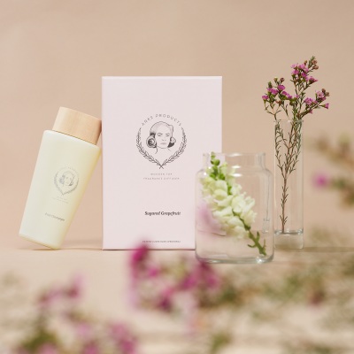 Skincare bottle styled with a branded card and flowers. By Nick van der Touw.