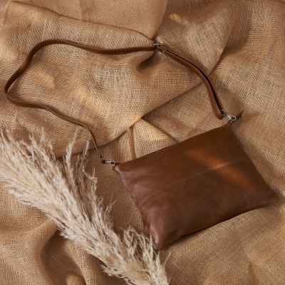 Product shot of a jute drawstring bag and leather goods on grasses. By Nick van der Touw.