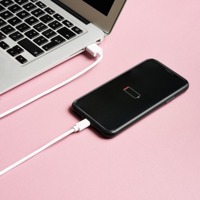 Product shot of a smartphone charging on a pink surface. By Nick van der Touw.