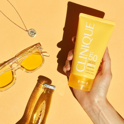 Suncare shot of Clinique SPF 50 held with yellow sunglasses. By Nick van der Touw.