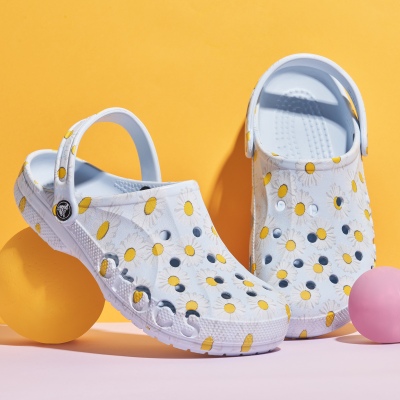 Product shot of white polka-dot clogs with charms. By Nick van der Touw.