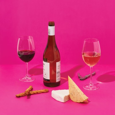 Product wine shot of red and rose bottles with glasses on pink. By Nick van der Touw.