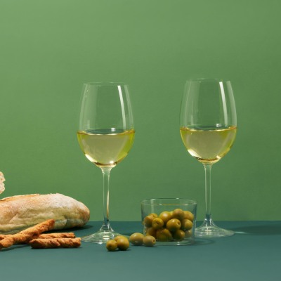 Product shot of white wine glasses on a green backdrop. By Nick van der Touw.