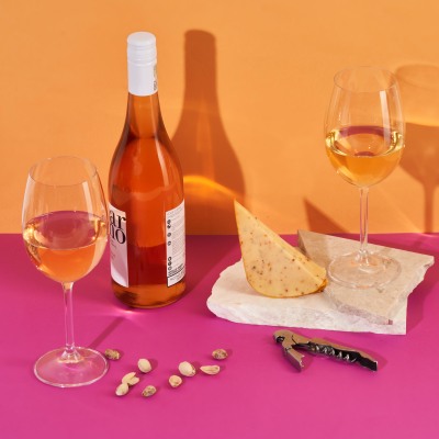 Product wine shot of rose with a glass and nachos on orange. By Nick van der Touw.