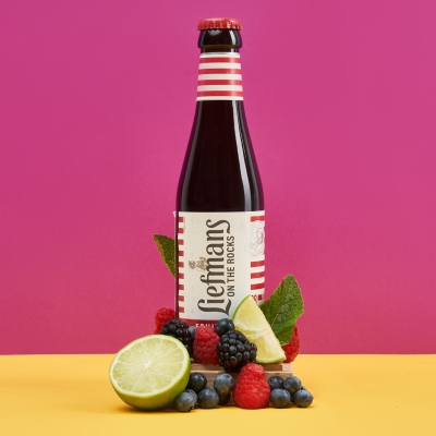 Product shot of a Liefmans fruit beer bottle on pink with mint. By Nick van der Touw.