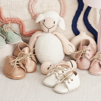 Product shot of crochet baby toys and shoes in pastel tones. By Nick van der Touw.
