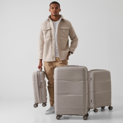 Travel product shot of a grey hardshell suitcase with a model. By Nick van der Touw.