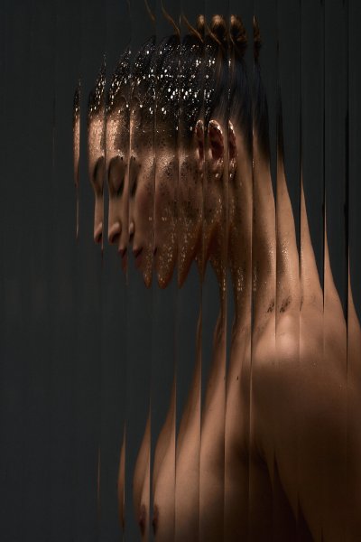 Moody beauty portrait of Albina in profile, lit through a fringed curtain. Studio editorial by Nick van der Touw.