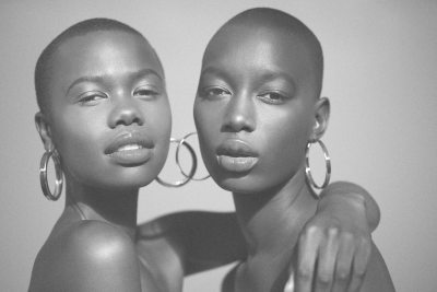 Beauty close-up of two models wearing statement hoop earrings. Studio editorial by Nick van der Touw.