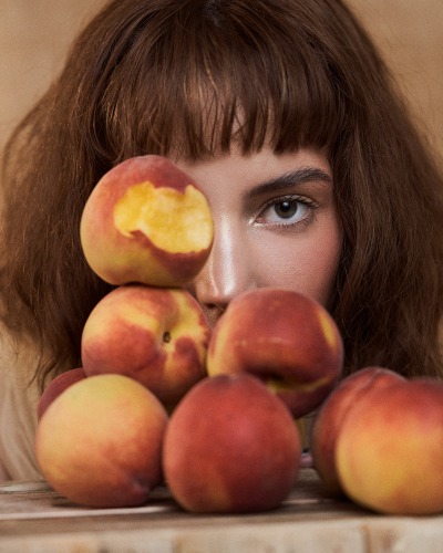 Beauty portrait of Franchesca styled with ripe peaches. Conceptual editorial by Nick van der Touw.