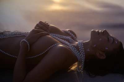 Editorial of Albina lying with pearls across a sand surface. Coastal photography by Nick van der Touw.