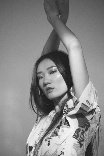 Studio editorial figure with arm raised in low key light. Black and white photography by Nick van der Touw.